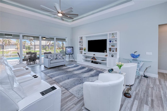 living room with ceiling fan, a raised ceiling, and light hardwood / wood-style floors