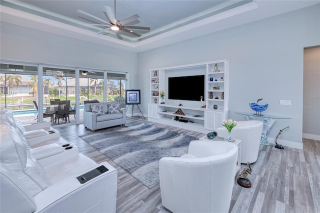 1450 Kiwi Ct, Punta Gorda, FL 33950 - living room featuring a ceiling fan, light wood-style floors, a tray ceiling, a towering ceiling, and baseboards
