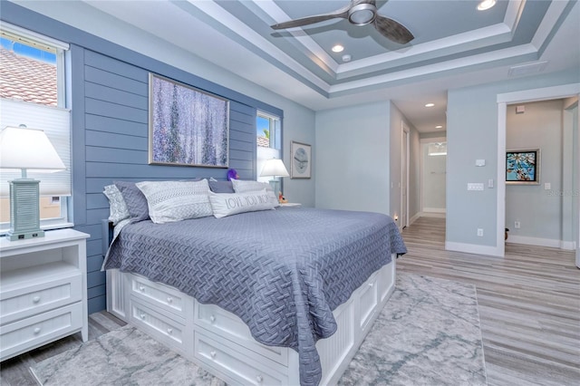 bedroom featuring light hardwood / wood-style floors, a raised ceiling, and ceiling fan