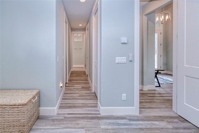 1450 Kiwi Ct, Punta Gorda, FL 33950 - corridor featuring a chandelier, light wood finished floors, and baseboards