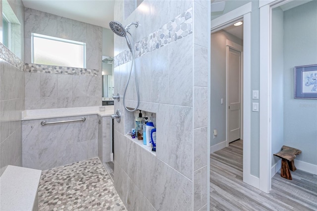 bathroom with a tile shower and wood-type flooring