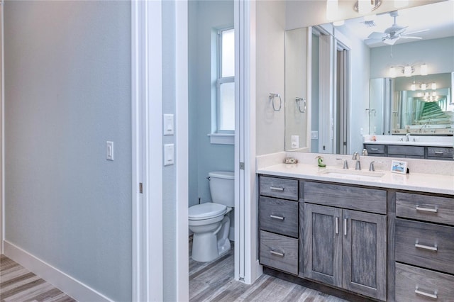 bathroom with vanity, hardwood / wood-style flooring, toilet, and ceiling fan