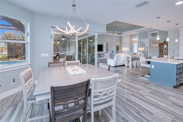 dining room featuring ceiling fan with notable chandelier, light hardwood / wood-style floors, and sink