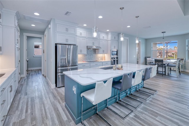 kitchen featuring pendant lighting, a large island, a breakfast bar, light wood-type flooring, and stainless steel appliances