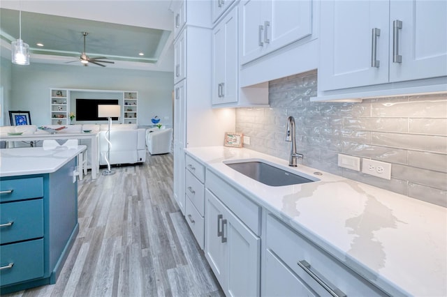 kitchen with ceiling fan, sink, decorative light fixtures, light hardwood / wood-style floors, and white cabinetry