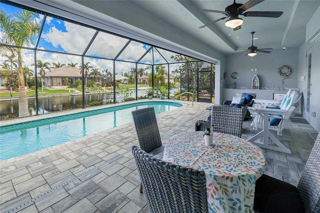 view of swimming pool with a water view, glass enclosure, ceiling fan, and a patio area