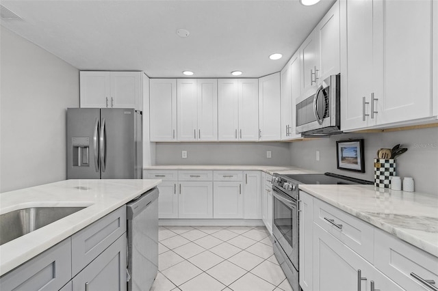 kitchen featuring white cabinetry, light stone countertops, light tile patterned flooring, and stainless steel appliances