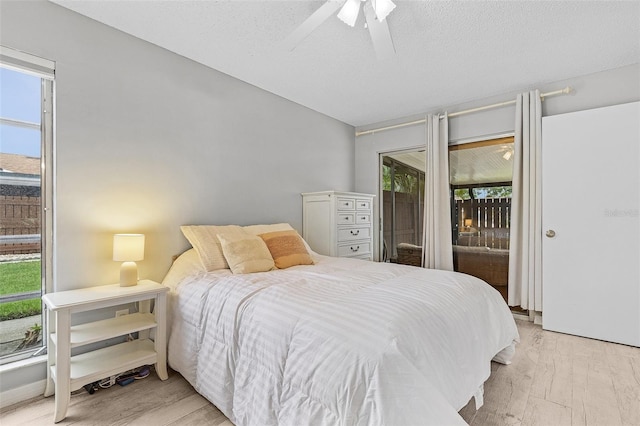 bedroom featuring ceiling fan, a textured ceiling, access to exterior, and light wood-type flooring