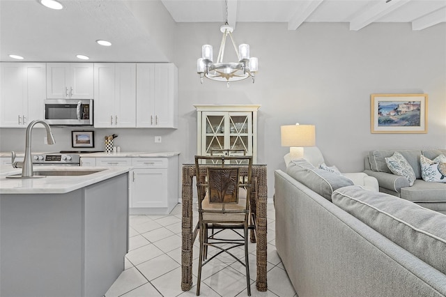 kitchen featuring stainless steel appliances, white cabinets, light tile patterned floors, beam ceiling, and pendant lighting