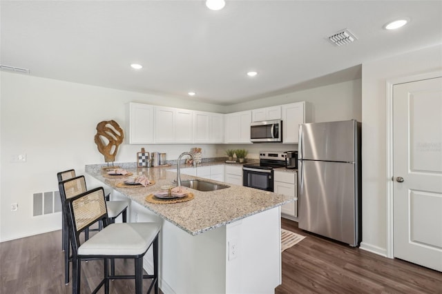 16307 Alcira Cir, Punta Gorda, FL 33955 - kitchen with stainless steel appliances, a peninsula, a kitchen breakfast bar, white cabinets, and light stone counters
