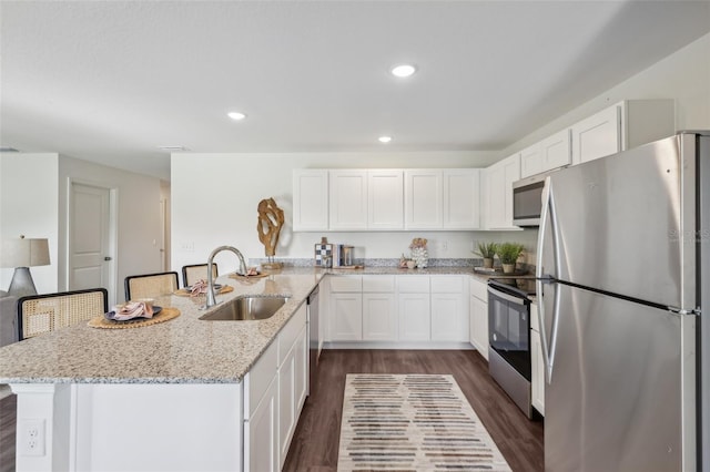 16307 Alcira Cir, Punta Gorda, FL 33955 - kitchen with stainless steel appliances, a peninsula, dark wood finished floors, white cabinets, and light stone countertops