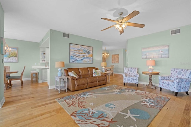 living room featuring ceiling fan with notable chandelier and hardwood / wood-style flooring