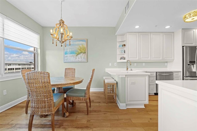 dining area with light hardwood / wood-style flooring, a notable chandelier, and sink