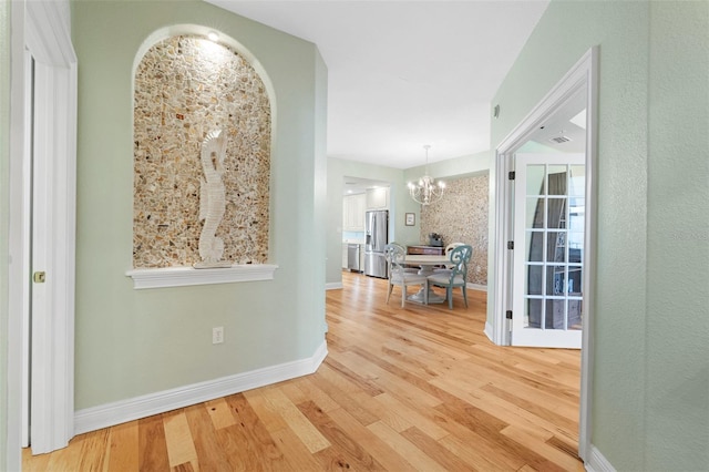 hallway with hardwood / wood-style flooring and a chandelier