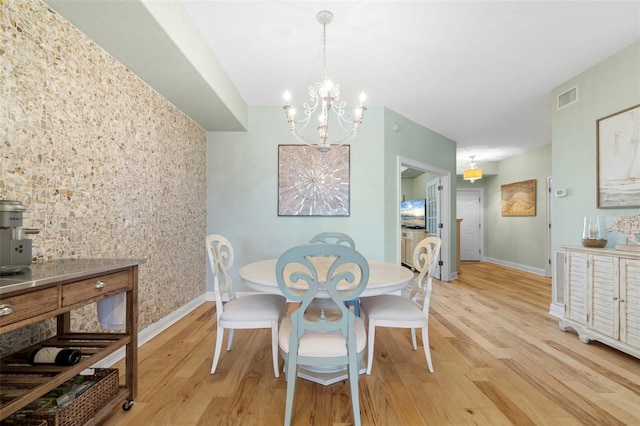 dining room with light wood-type flooring and a chandelier