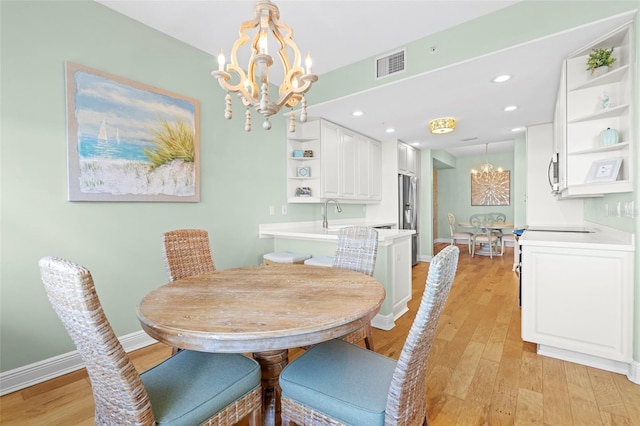 dining room with light wood-type flooring and an inviting chandelier