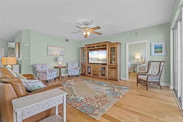 living room with ceiling fan and light hardwood / wood-style flooring