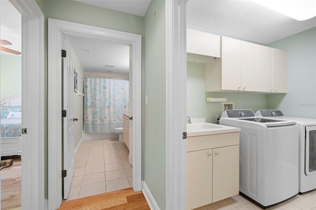 clothes washing area featuring cabinets, sink, ceiling fan, independent washer and dryer, and light hardwood / wood-style flooring