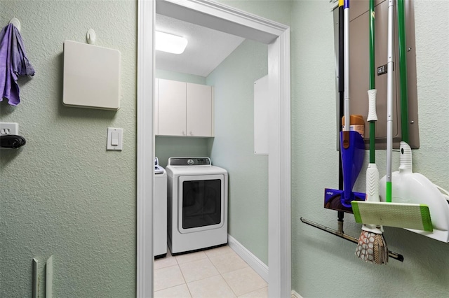 laundry room featuring cabinets, a textured ceiling, light tile patterned floors, and washer and clothes dryer