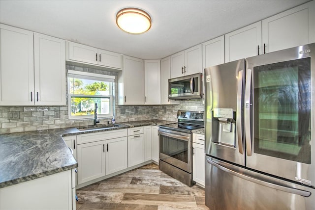 kitchen with light wood-type flooring, white cabinetry, sink, and stainless steel appliances