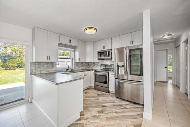 kitchen with white cabinetry, stainless steel appliances, light tile patterned flooring, and tasteful backsplash