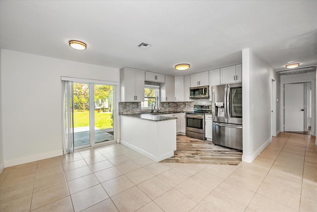 kitchen with stainless steel appliances, sink, tasteful backsplash, light tile patterned floors, and white cabinets