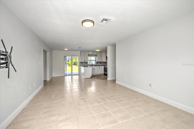 unfurnished living room with a textured ceiling and light tile patterned floors