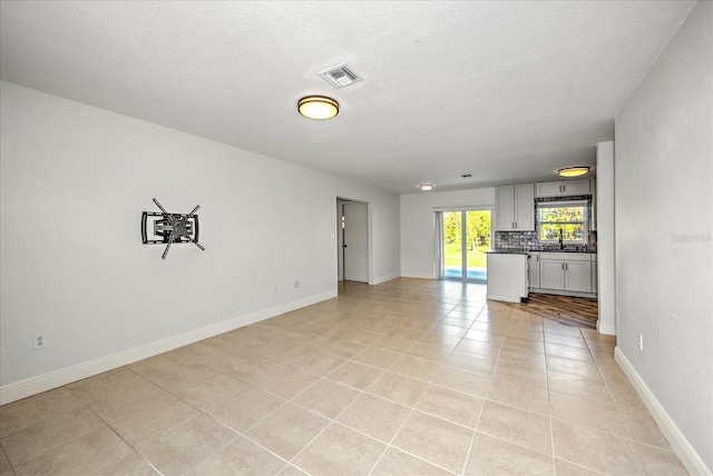 unfurnished living room featuring a textured ceiling, light tile patterned floors, and sink