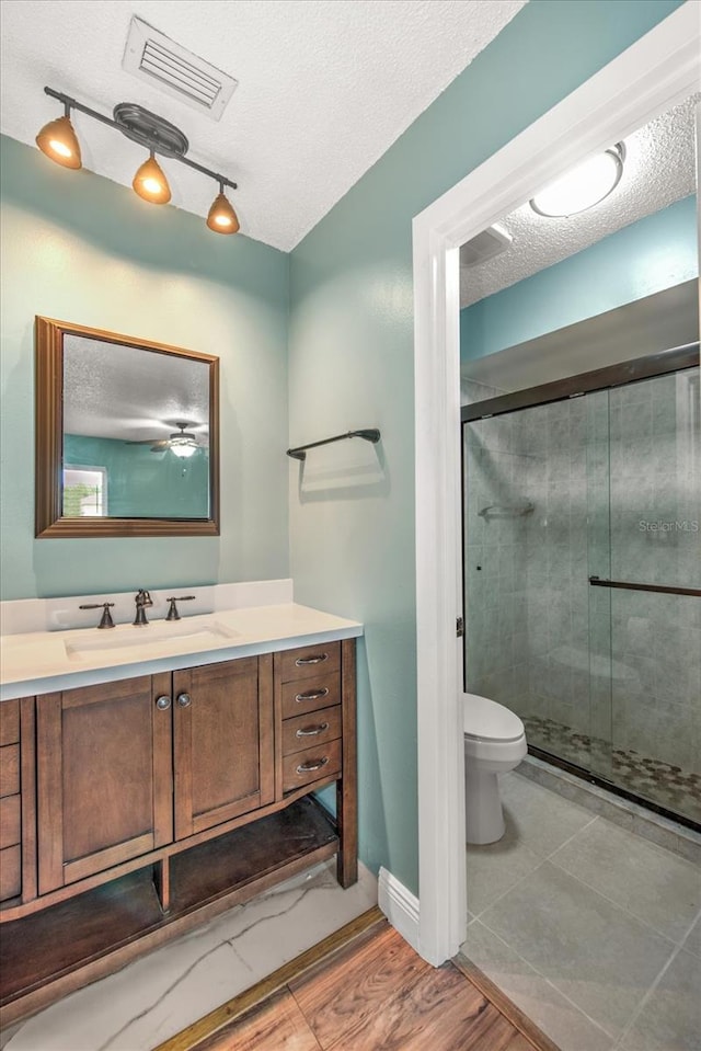 bathroom with walk in shower, toilet, hardwood / wood-style floors, and a textured ceiling