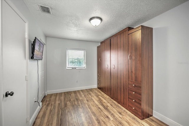 unfurnished bedroom featuring a textured ceiling, a closet, and light hardwood / wood-style flooring