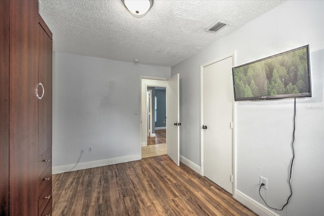 unfurnished bedroom with dark hardwood / wood-style flooring and a textured ceiling