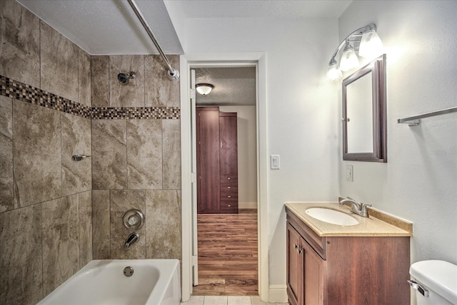 full bathroom featuring vanity, a textured ceiling, hardwood / wood-style floors, toilet, and tiled shower / bath