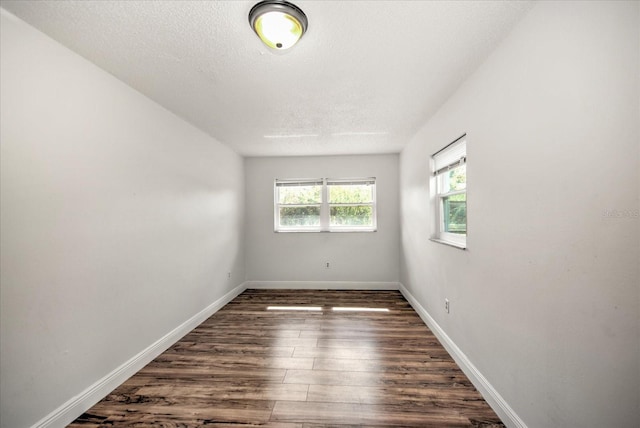 empty room featuring a textured ceiling and dark hardwood / wood-style floors