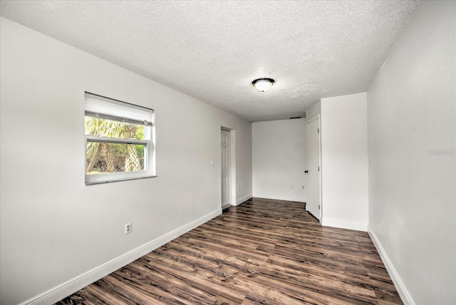 empty room with dark wood-type flooring and a textured ceiling