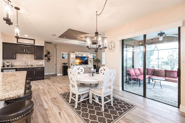 dining area featuring sink, ceiling fan with notable chandelier, and light hardwood / wood-style flooring