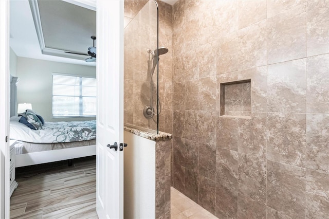 bathroom featuring ceiling fan, tiled shower, and a raised ceiling