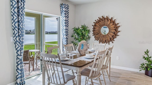 dining room featuring light hardwood / wood-style flooring and a water view