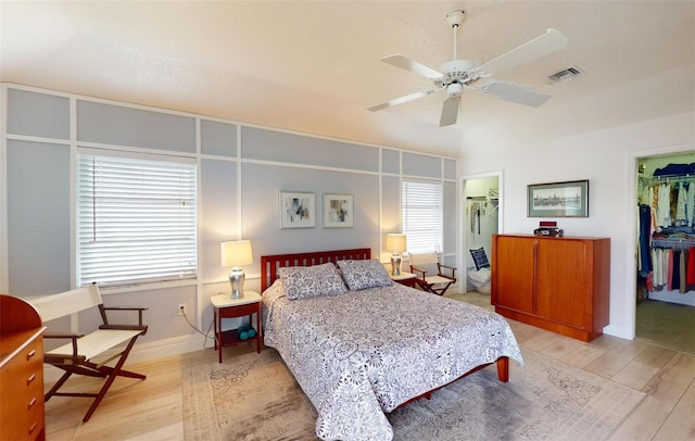 bedroom featuring a walk in closet, a closet, and light hardwood / wood-style flooring