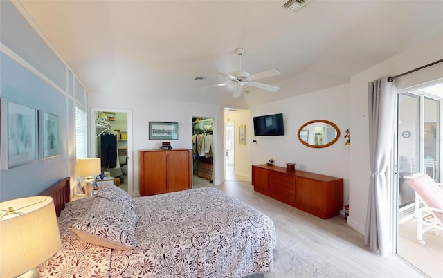 bedroom featuring a spacious closet, a closet, ceiling fan, and light hardwood / wood-style floors