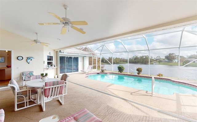 view of pool featuring glass enclosure, a patio area, a water view, and ceiling fan