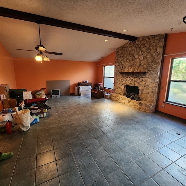 unfurnished living room with ceiling fan, vaulted ceiling with beams, a healthy amount of sunlight, and a textured ceiling