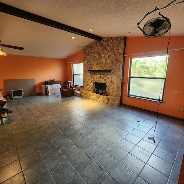 unfurnished living room with lofted ceiling with beams, a wealth of natural light, a textured ceiling, and a fireplace