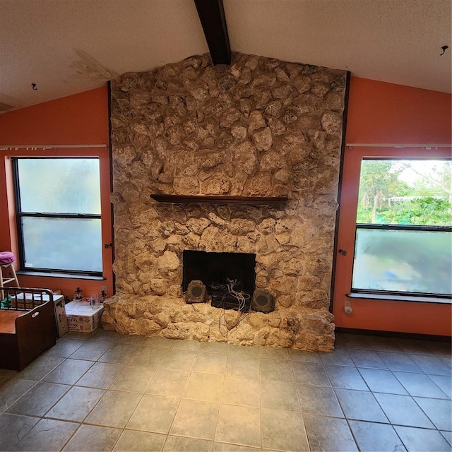 unfurnished living room featuring a stone fireplace, a textured ceiling, and vaulted ceiling with beams