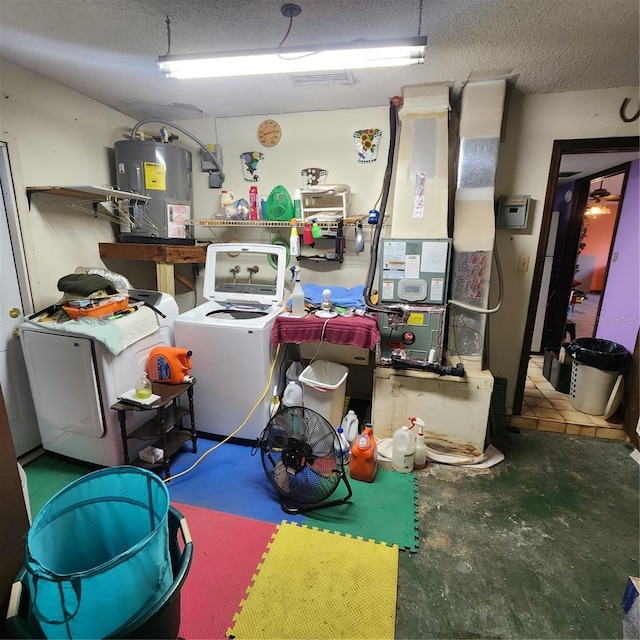 interior space featuring washing machine and clothes dryer, water heater, and a textured ceiling