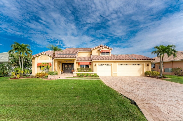 mediterranean / spanish house featuring a garage and a front lawn