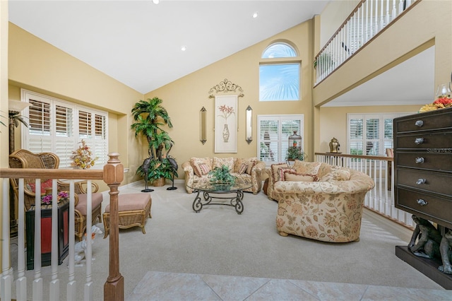 living room with high vaulted ceiling, a wealth of natural light, and light carpet