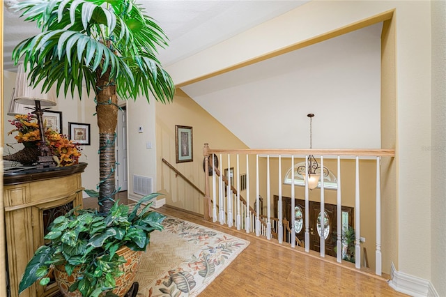 corridor featuring wood-type flooring, a notable chandelier, and vaulted ceiling