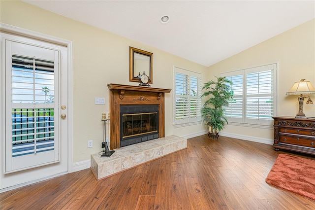 living room featuring hardwood / wood-style flooring, a tile fireplace, and vaulted ceiling