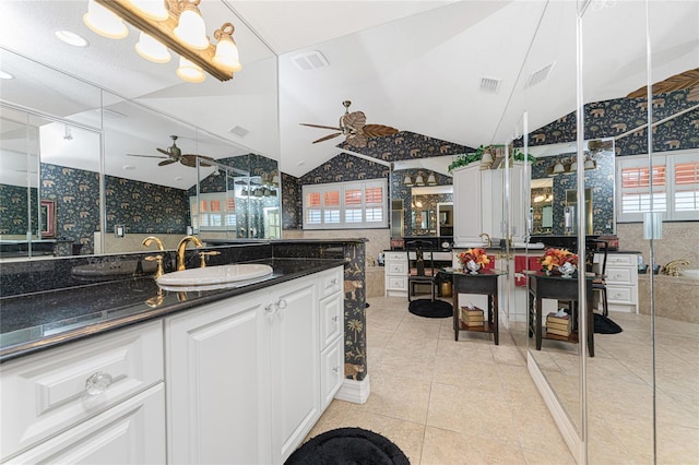 kitchen featuring dark stone counters, decorative light fixtures, light tile patterned floors, sink, and white cabinets