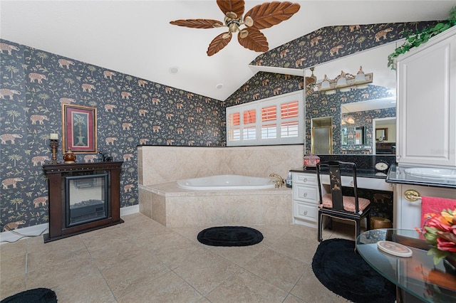 bathroom featuring lofted ceiling, tiled tub, ceiling fan, and vanity